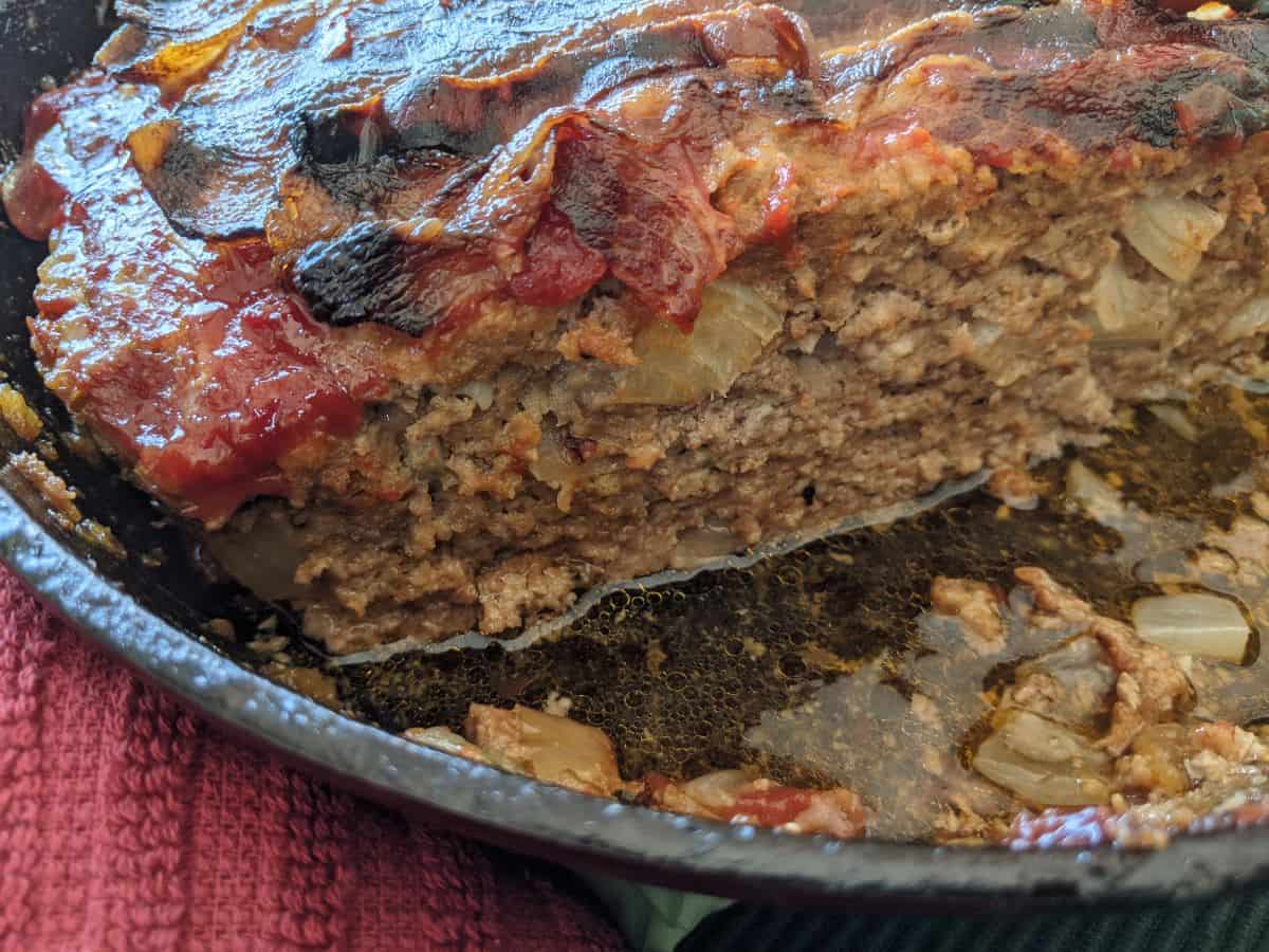 meatloaf cut in half showing the inside of it in a cast iron skillet.