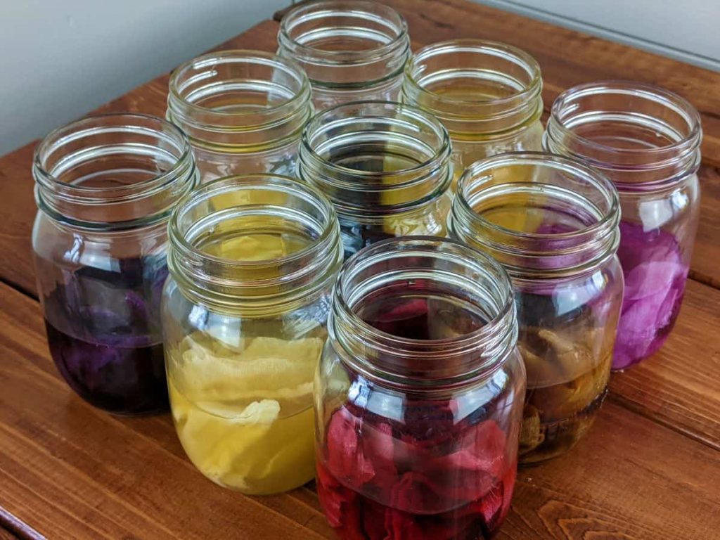 mason jars of natural dye made using food from the kitchen with pieces of cloth in them
