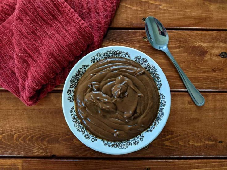 chocolate avocado pudding in a dish with a spoon and a napkin on a table