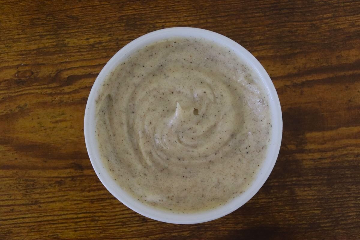 Bowl of creamy coleslaw dressing on a wooden surface.