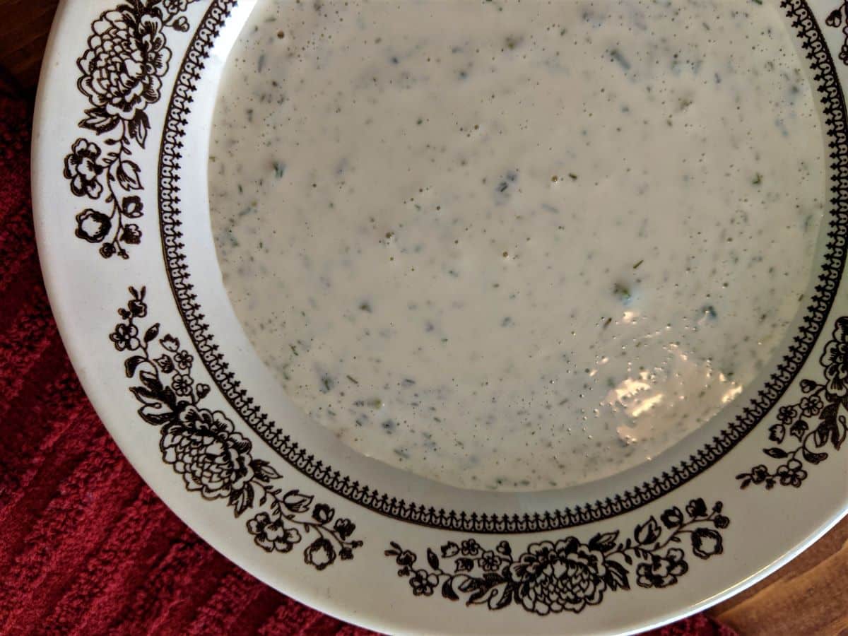 white dressing with herbs in it in a bowl.