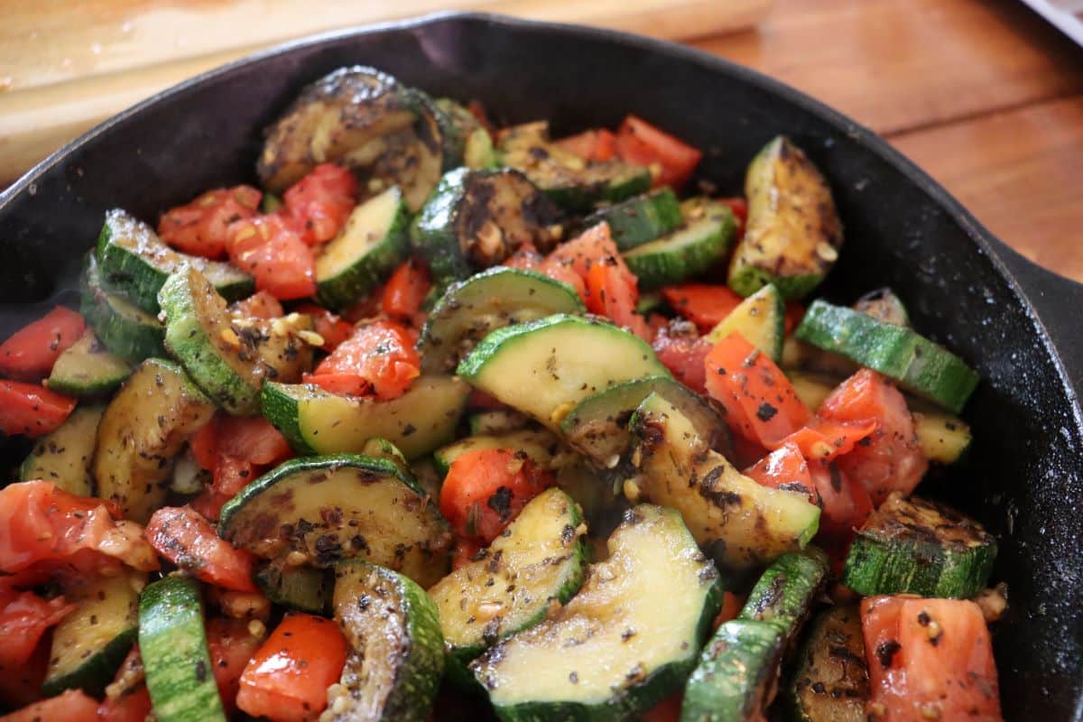 cooked and seasoned zucchini and tomatoes in a cast iron skillet.