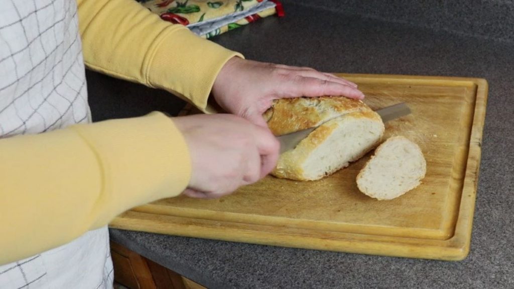 woman slicing a handmade loaf of bread