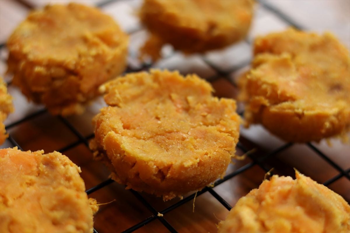 Round orange dog treats on a cooling rack.