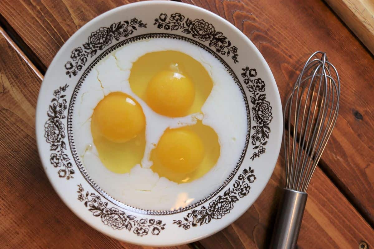 eggs and milk in a bowl with a whisk