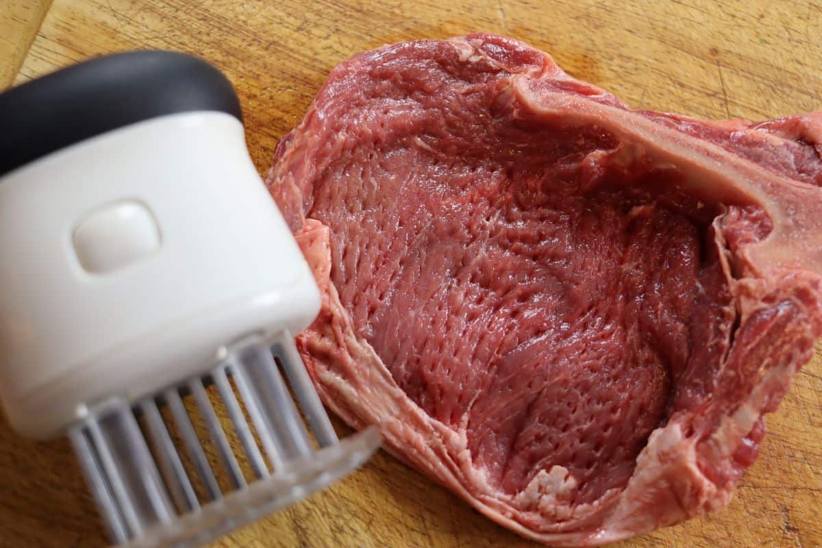 steak and a tenderizer on a cutting board