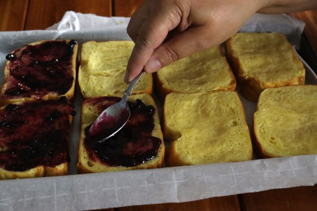 blueberry fruit spread being spooned onto bread