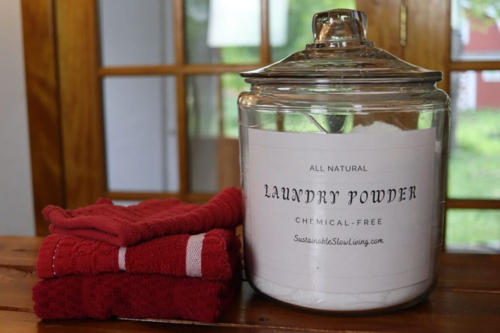 container of simple diy laundry powder on a table with towels