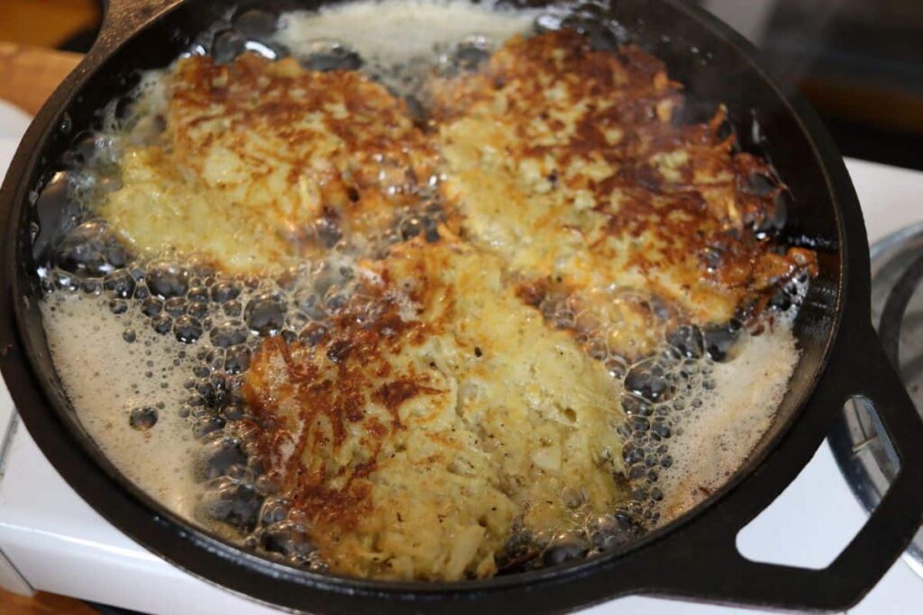 potato pancakes frying in a cast iron skillet