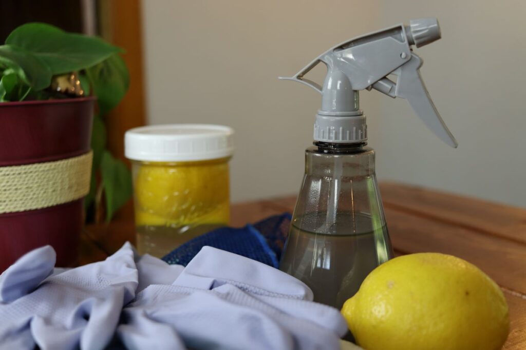 natural handmade kitchen degreaser in a bottle on a table with rubber gloves and lemons