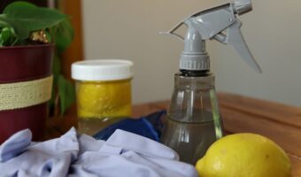 natural handmade kitchen degreaser in a bottle on a table with rubber gloves and lemons