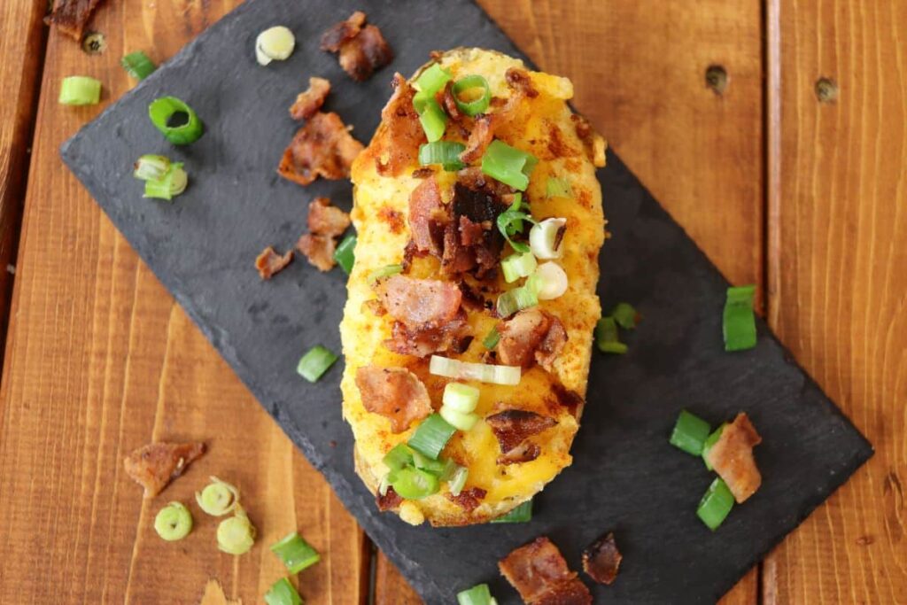 overhead view of a homemade classic twice baked potato on a slate serving board