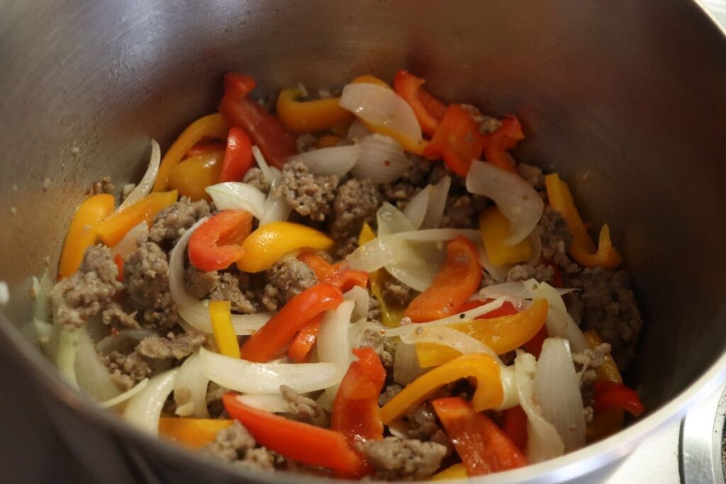 meat and vegetables for creamy sausage and pepper soup cooking in a pot