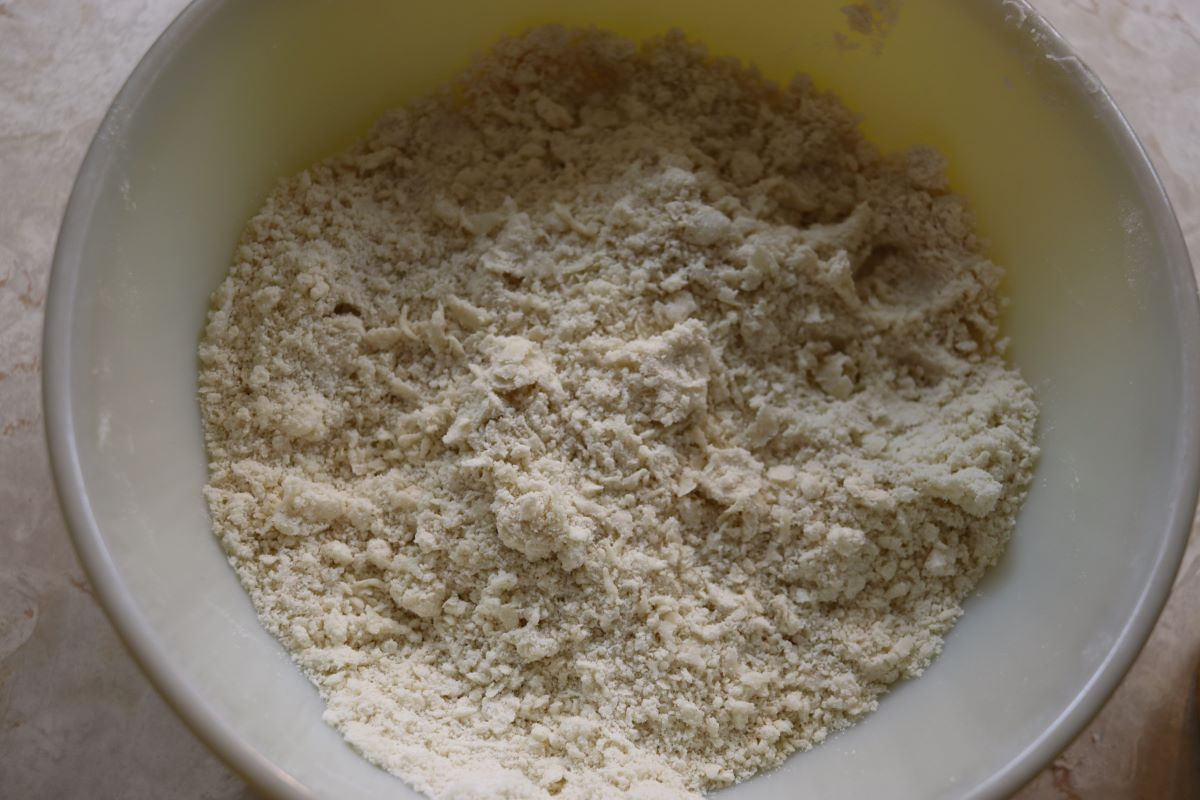 Bowl with flour with lard mixed into it in pea sized pieces.