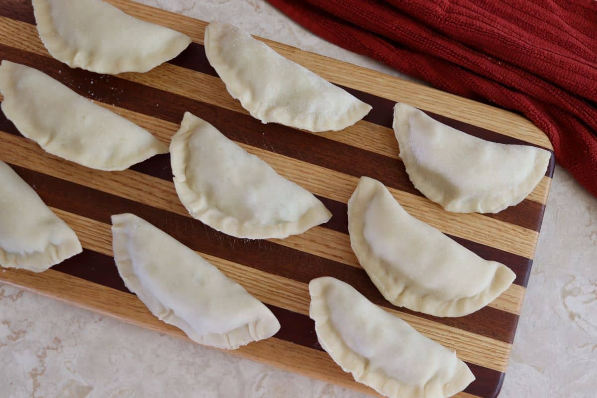 Small moon shaped dough pockets sitting on a striped cutting board.