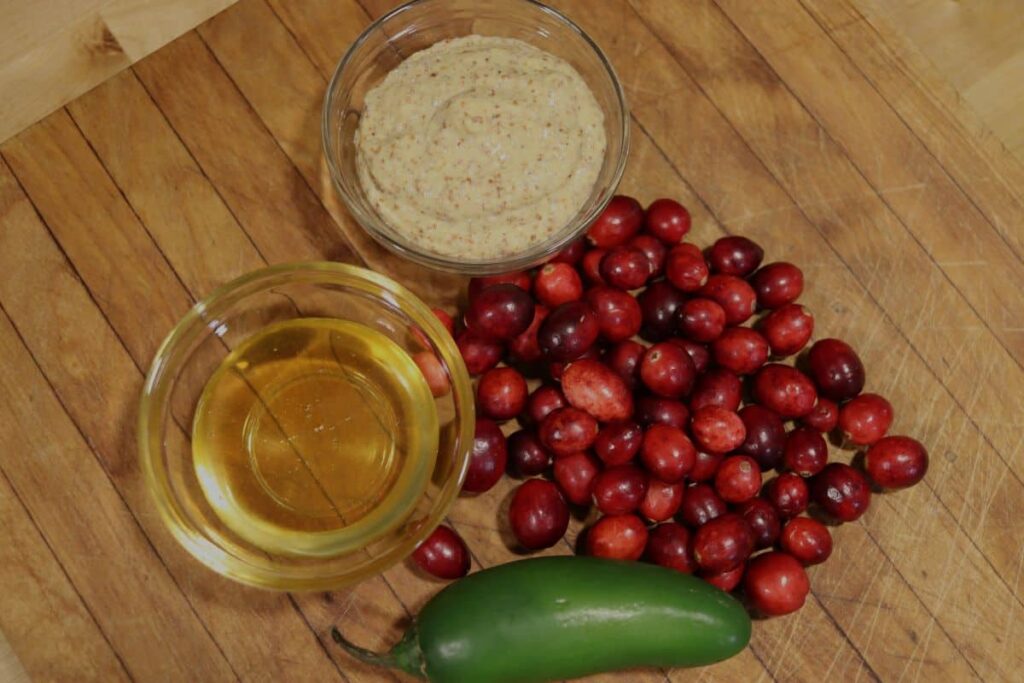 ingredients for a spicy cranberry mustard recipe on a cutting board