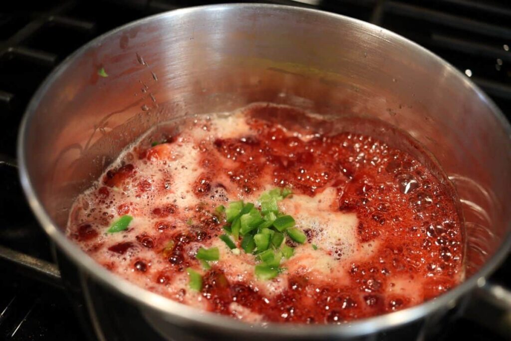 cranberries honey and jalapeno simmering in a pot