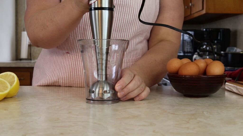 woman showing an immersion blender to be used to make homemade mayonnaise