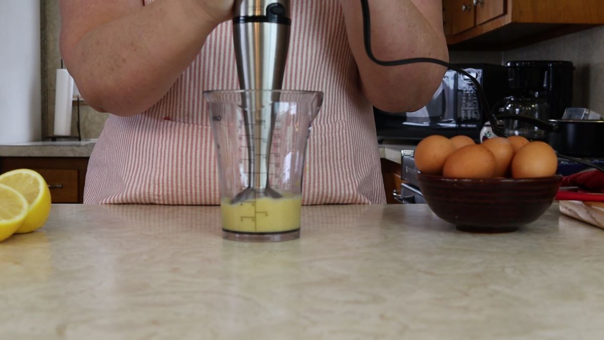 immersion blender in a blender cup with an egg mixture.