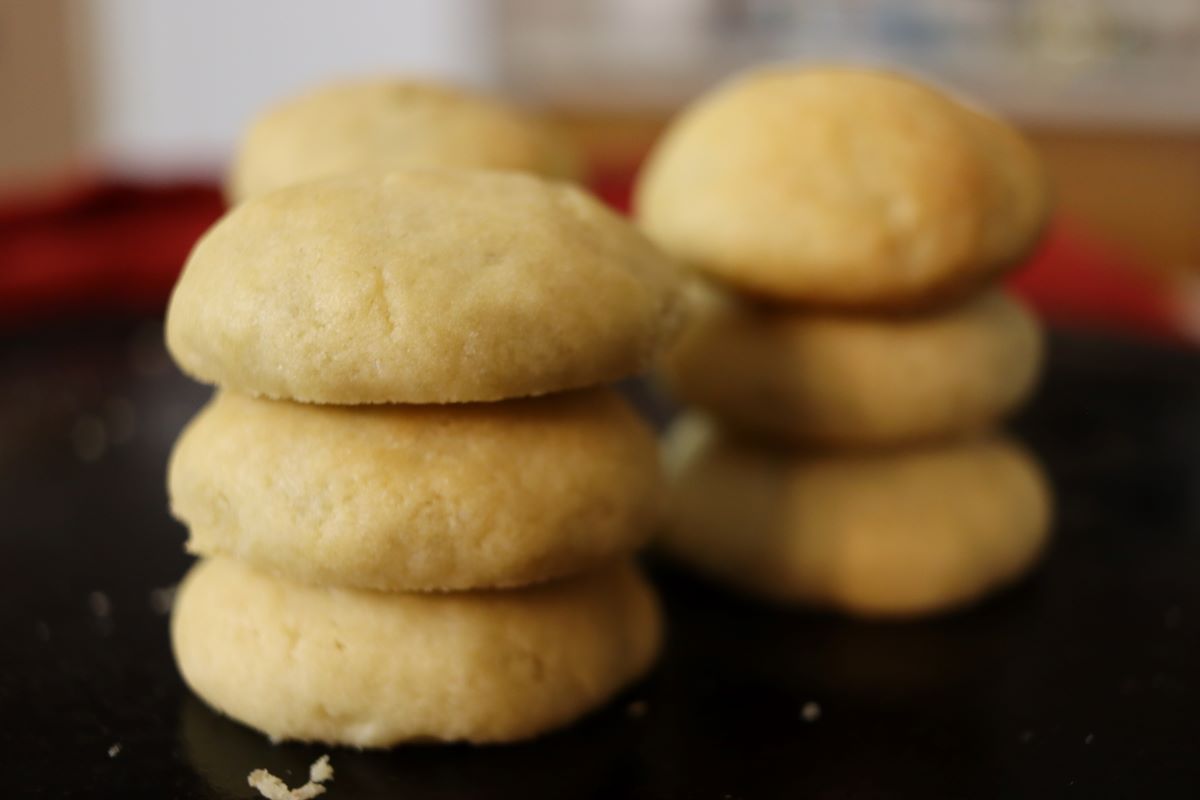 Stacks of light colored cookies on a dark surface.