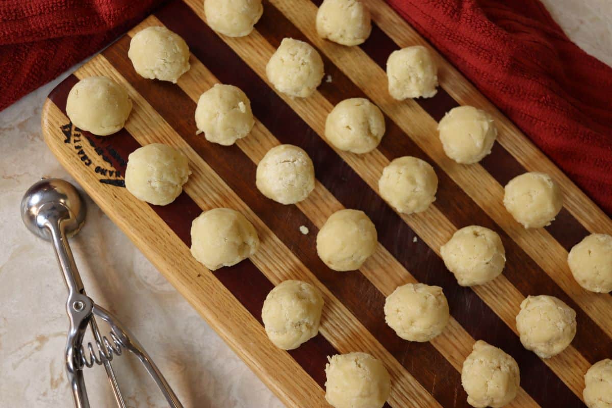 Small dough balls on a striped cutting board.