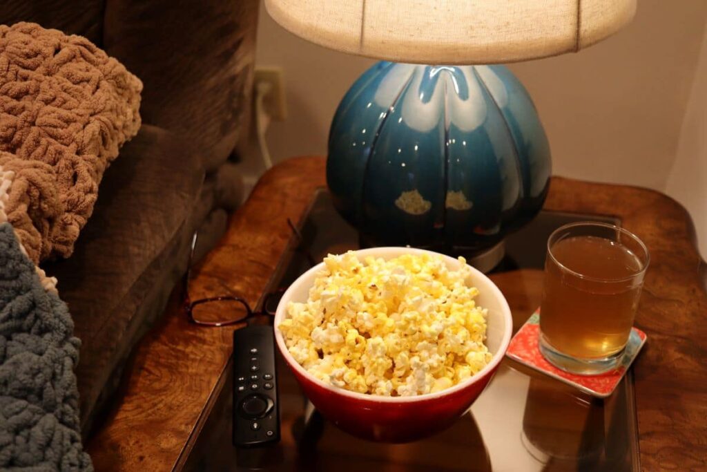 popcorn glasses and a beverage on a table for a movie night