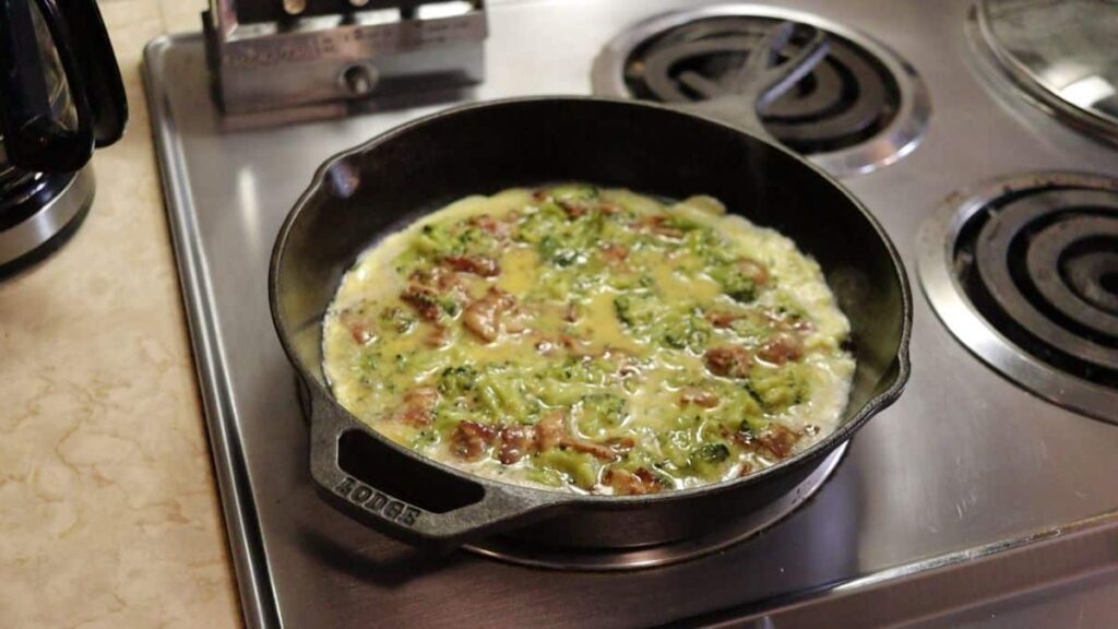 omelette mixture in a cast iron skillet pan on the stove