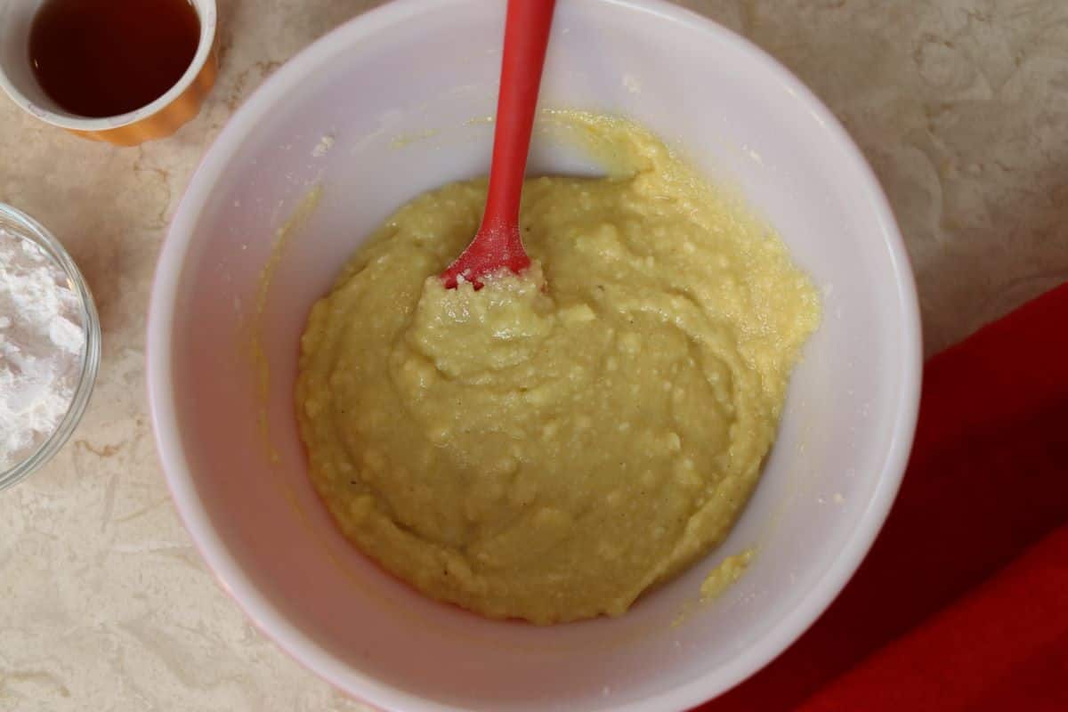 yellow cake batter in a bowl with a red spatula sitting in it.