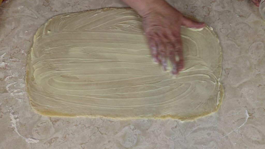 spreading butter over dough
