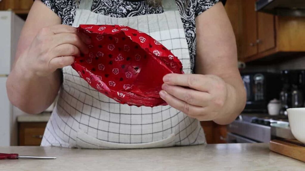 removing the balloon from the inside of a newly made fabric scrap mache bowl