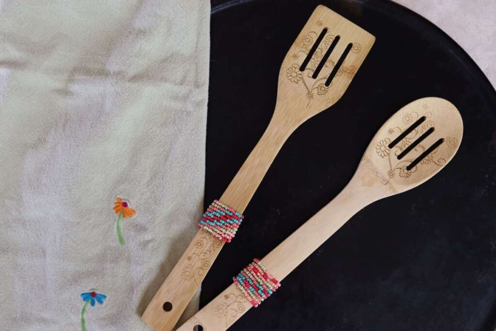 two diy beaded wooden spoons displayed on a counter