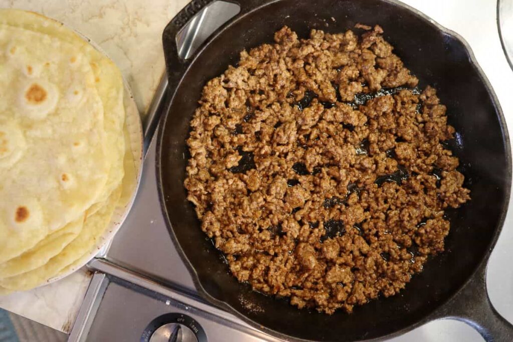 ground beef in a skillet with tortillas
