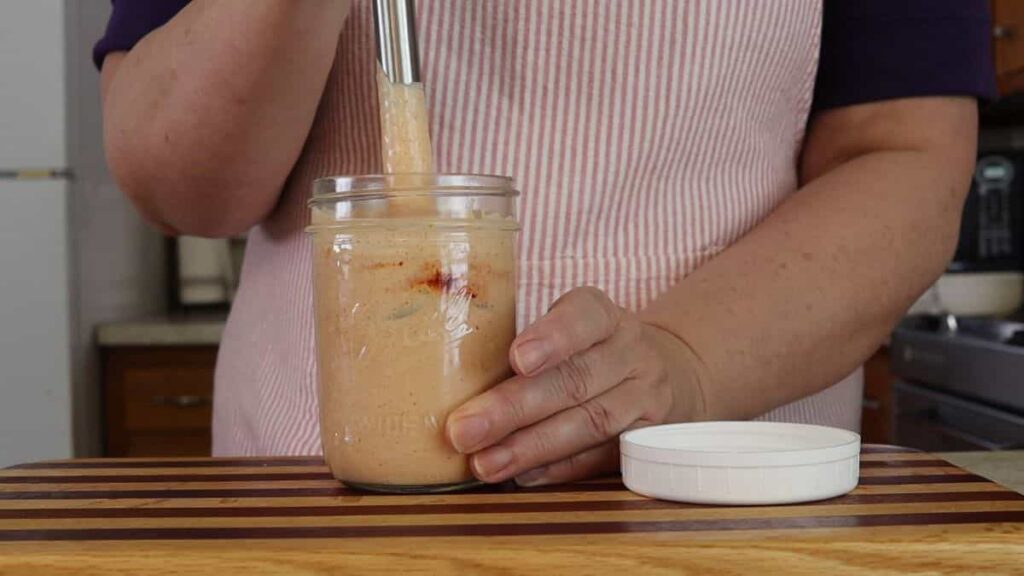woman blending homemade sauce in a mason jar