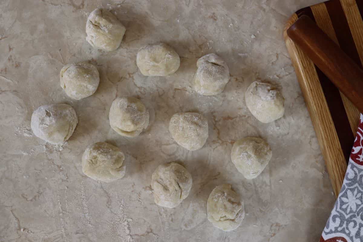 12 balls of dough sitting on a countertop.