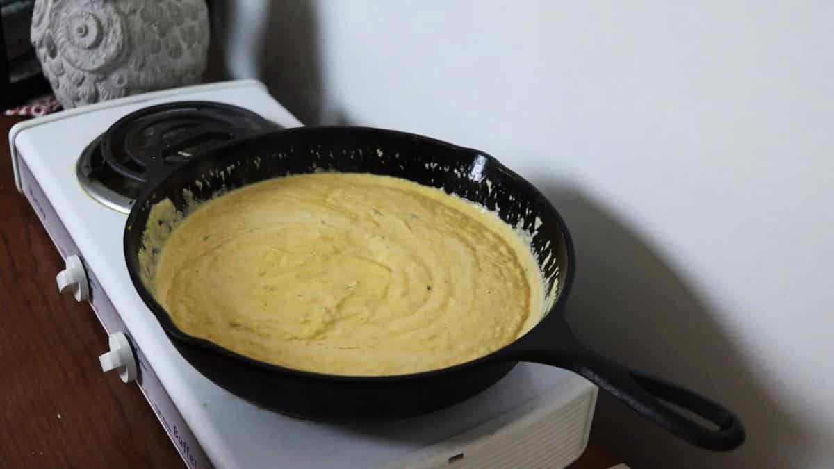 Light orange sauce in a cast iron skillet on a stovetop.