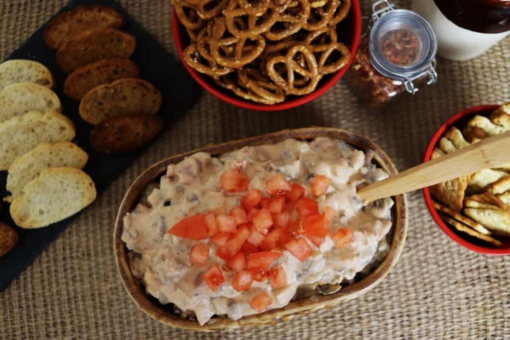 overview of sausage dip on a serving table with crackers and pretzels