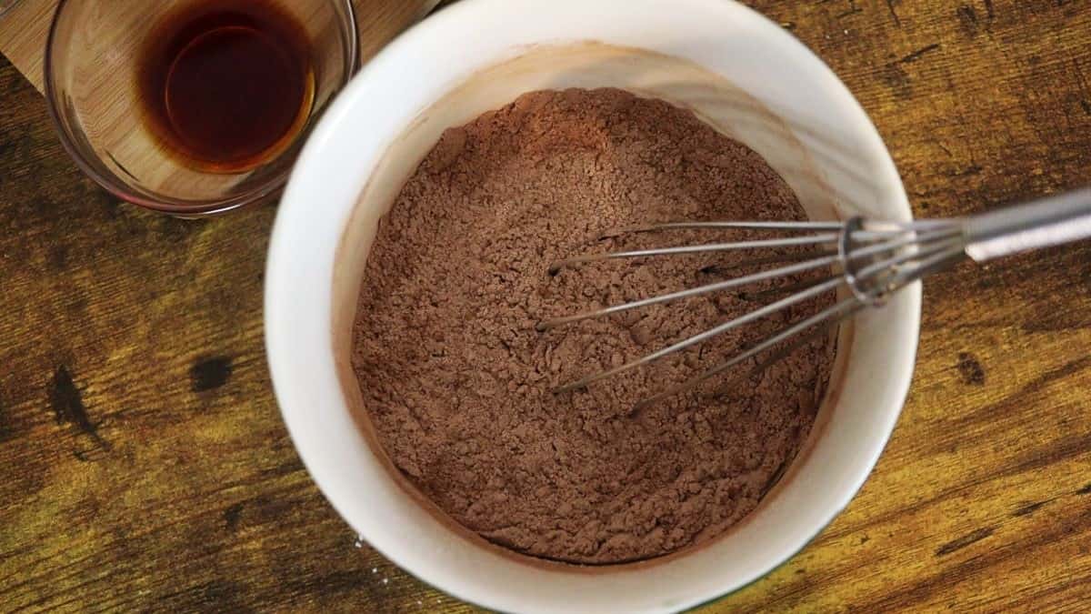 Brown powder in a white bowl with a whisk in it.