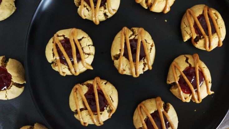 peanut butter and jelly thumbprint cookies on a black dish