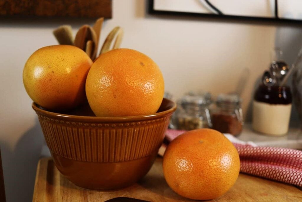 bowl of grapefruit with a grapefuit sitting next to it on a table.