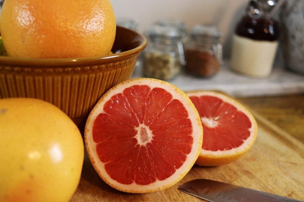 grapefruit cut in half sitting next to a bowl of grapefruit