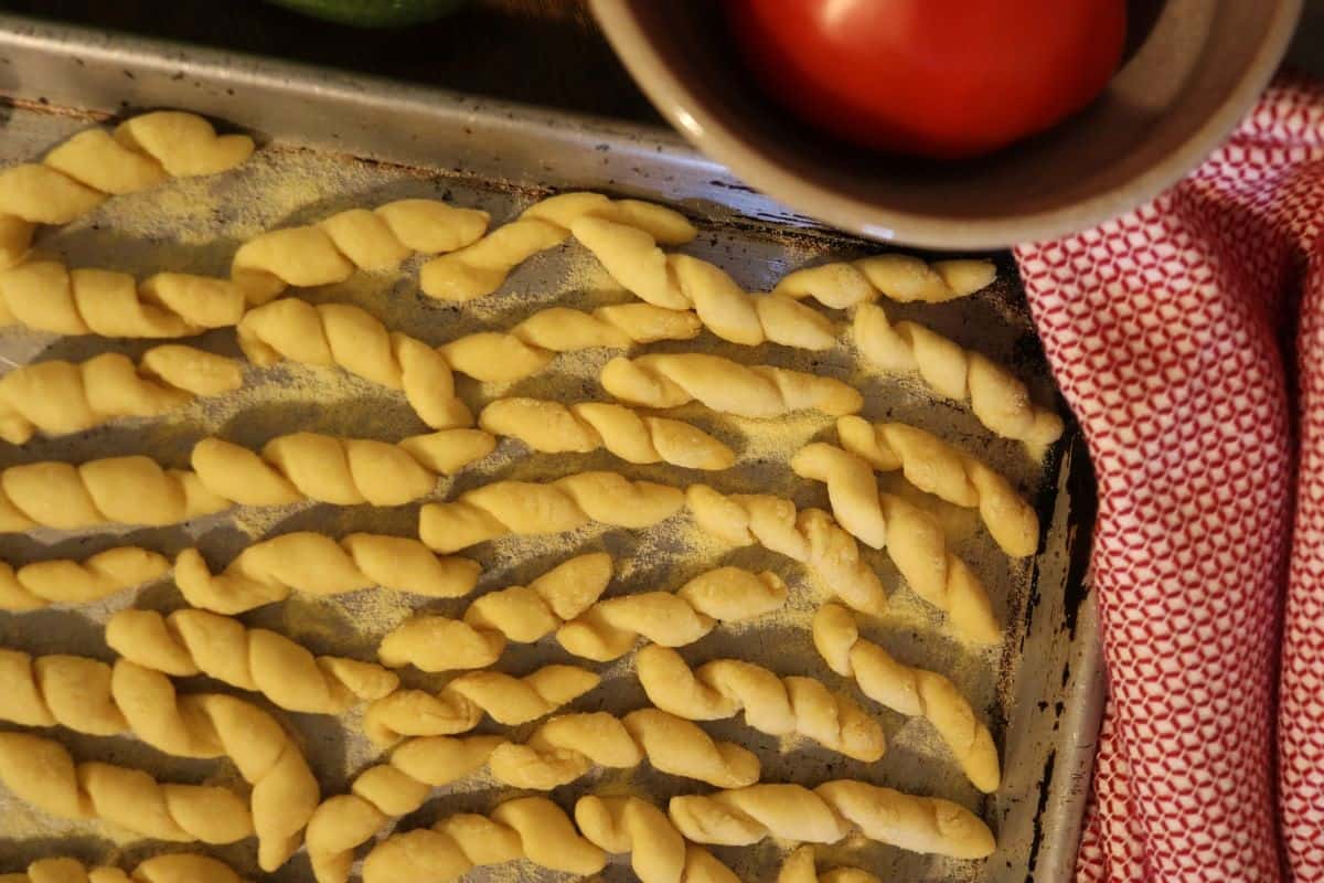 hand rolled pasta spread out on a floured sheet pan.