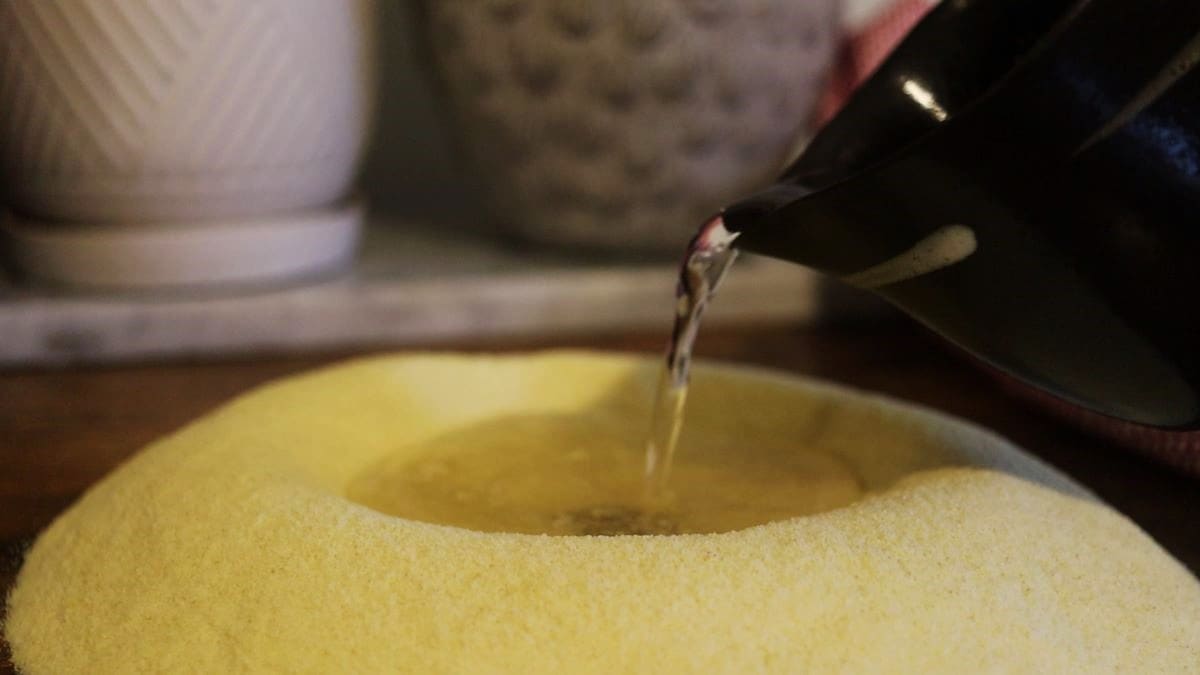 pouring water into a flour well made of yellow flour.