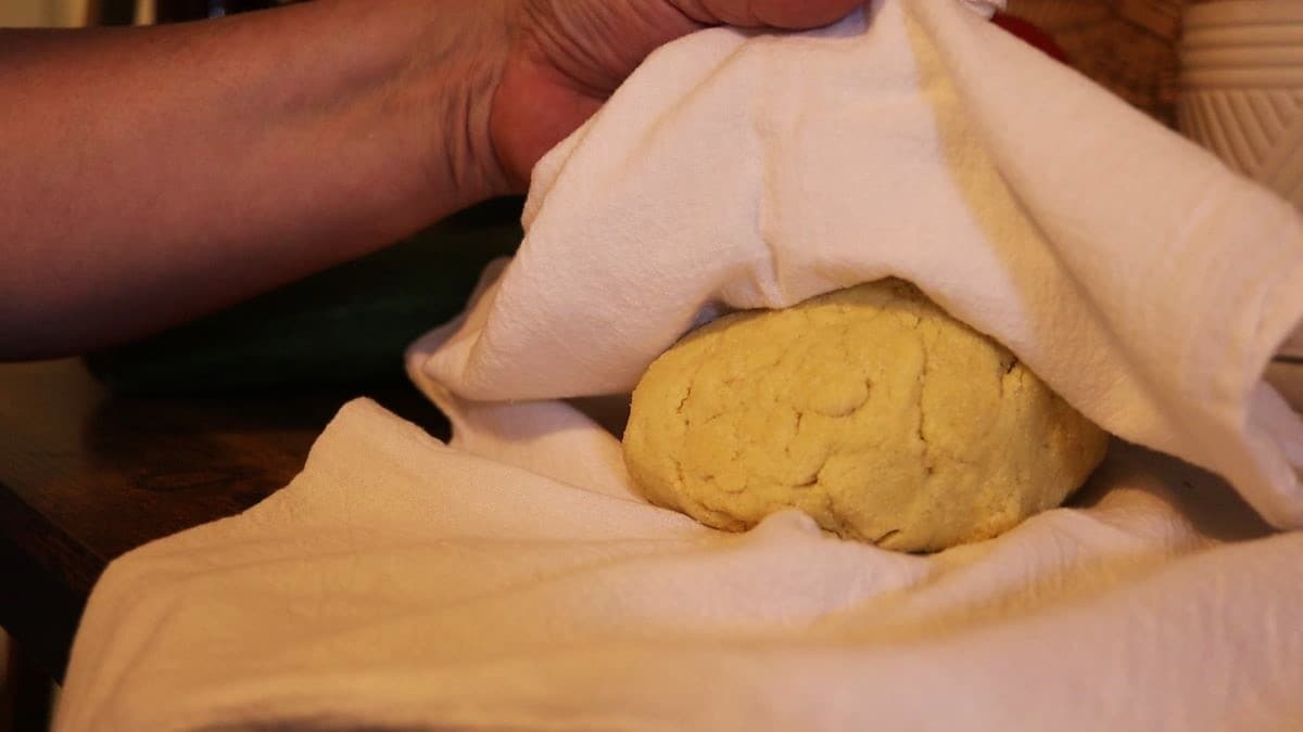 a ball of dough being covered in a flour sack towel.