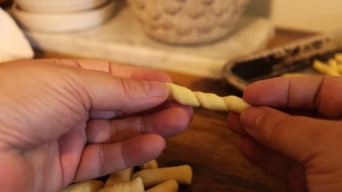 two hands holding a piece of hand rolled pasta between them.