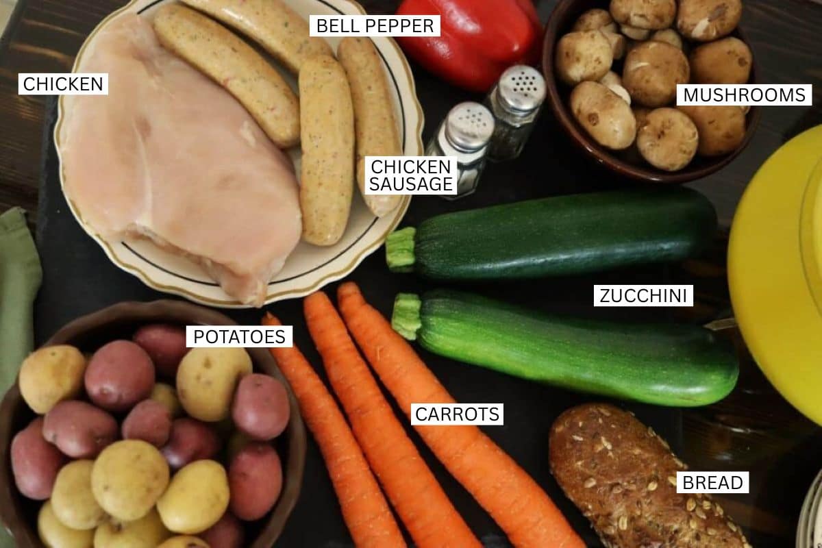 A variety of labeled ingredients on a table: raw chicken breast, chicken sausages, small red and yellow potatoes, whole carrots, zucchinis, mushrooms, a red bell pepper, salt and pepper shakers, and a loaf of bread.