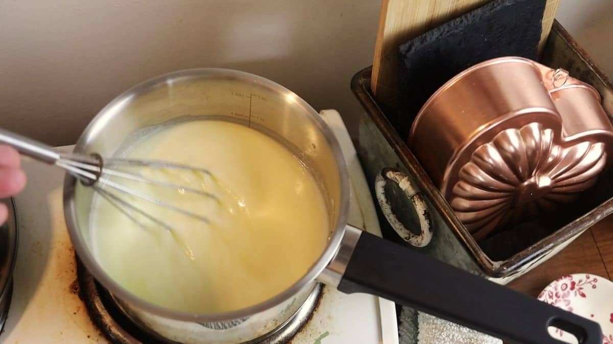 lemon syrup in a saucepan with a whisk in it sitting on a stovetop.
