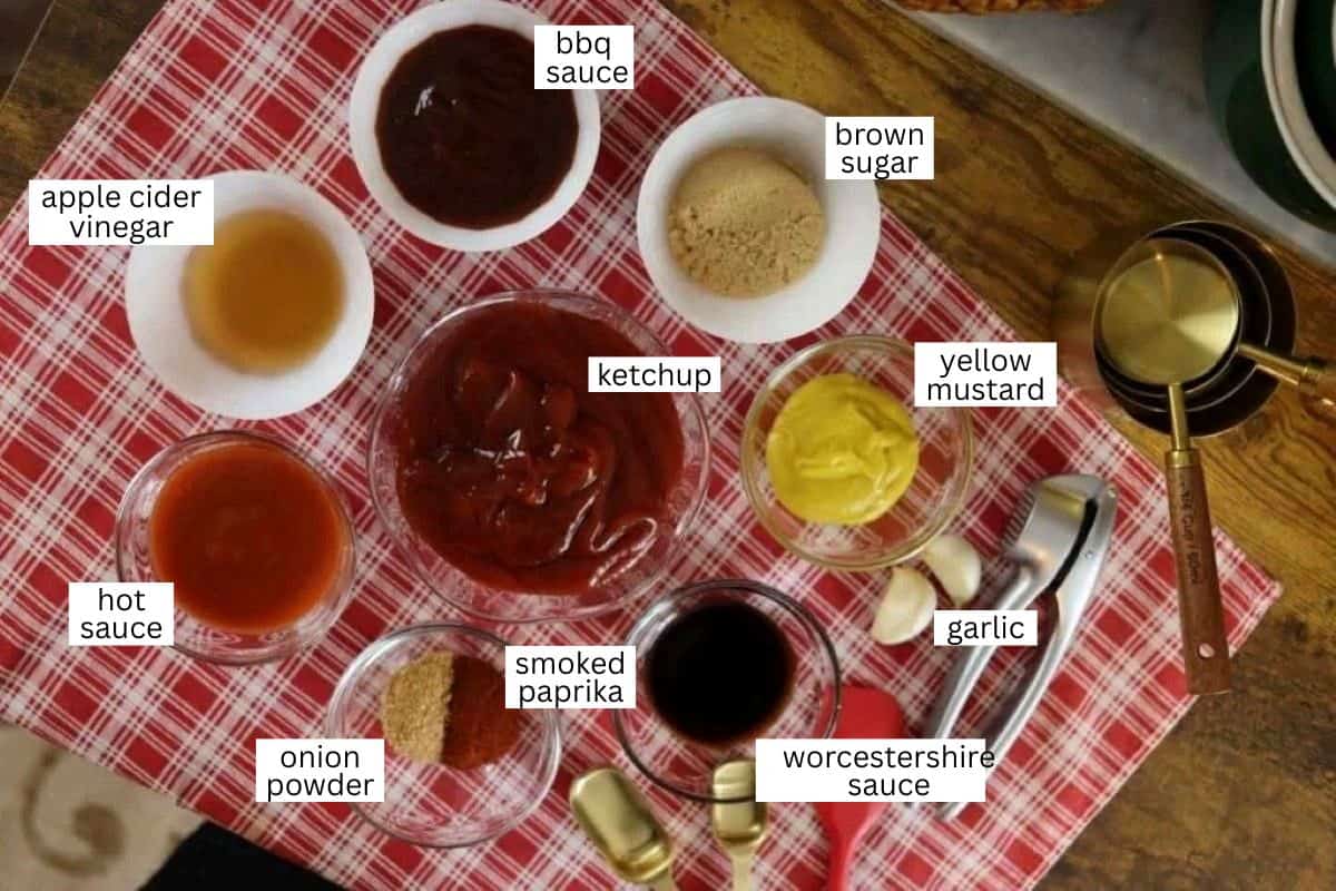 Small bowls on a red plaid cloth, each labeled with ingredients: apple cider vinegar, bbq sauce, brown sugar, ketchup, yellow mustard, hot sauce, smoked paprika, onion powder, garlic, and Worcestershire sauce.