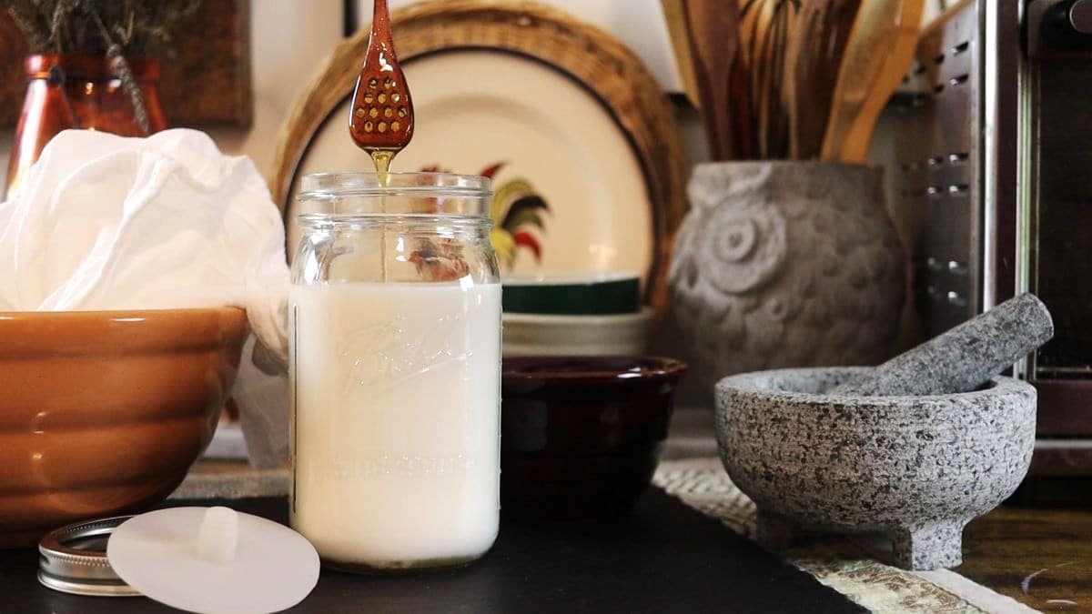 drizzling honey into a jar of almond milk.
