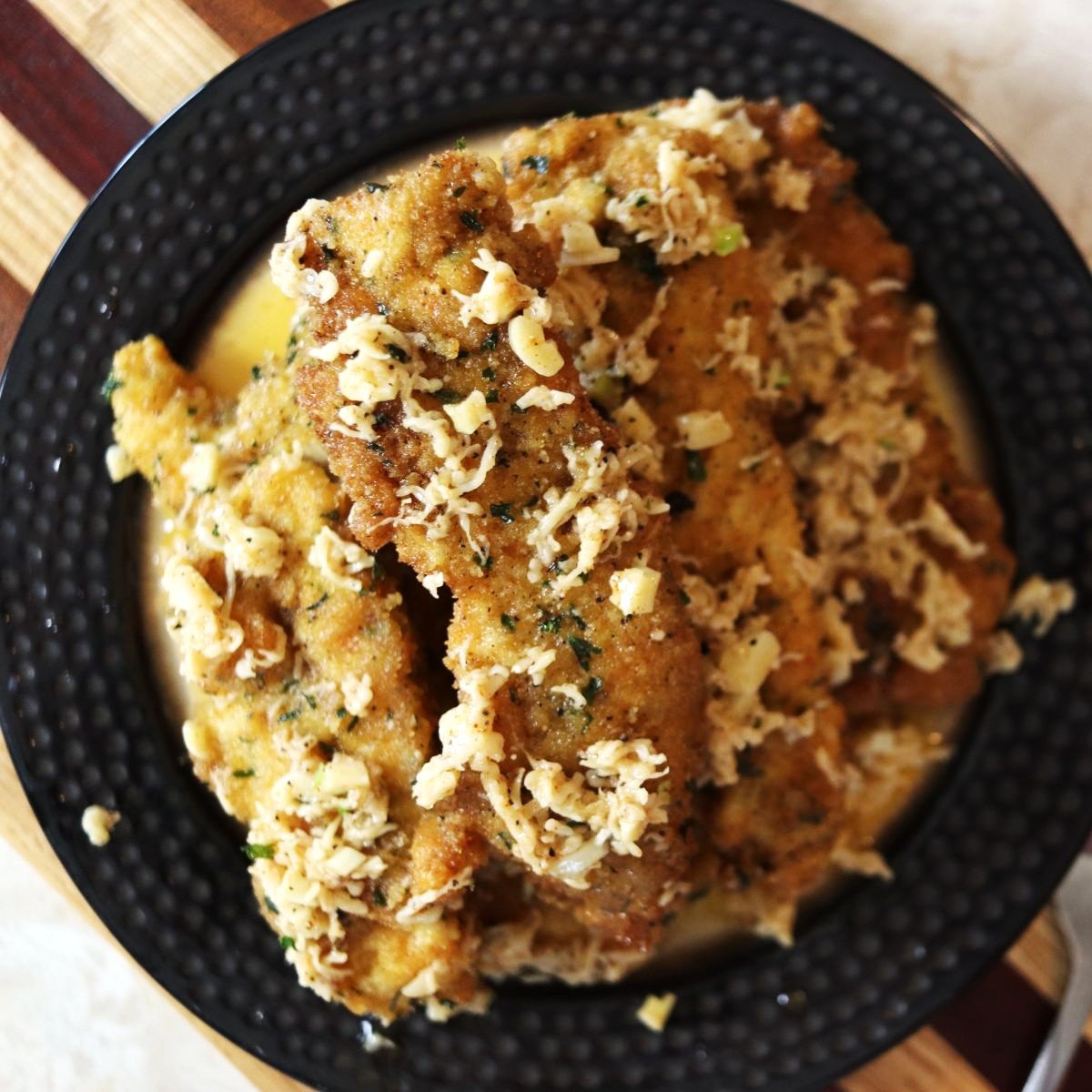 overview of a plate piled high with homemade chicken tenders rolled in garlic parmesan sauce.