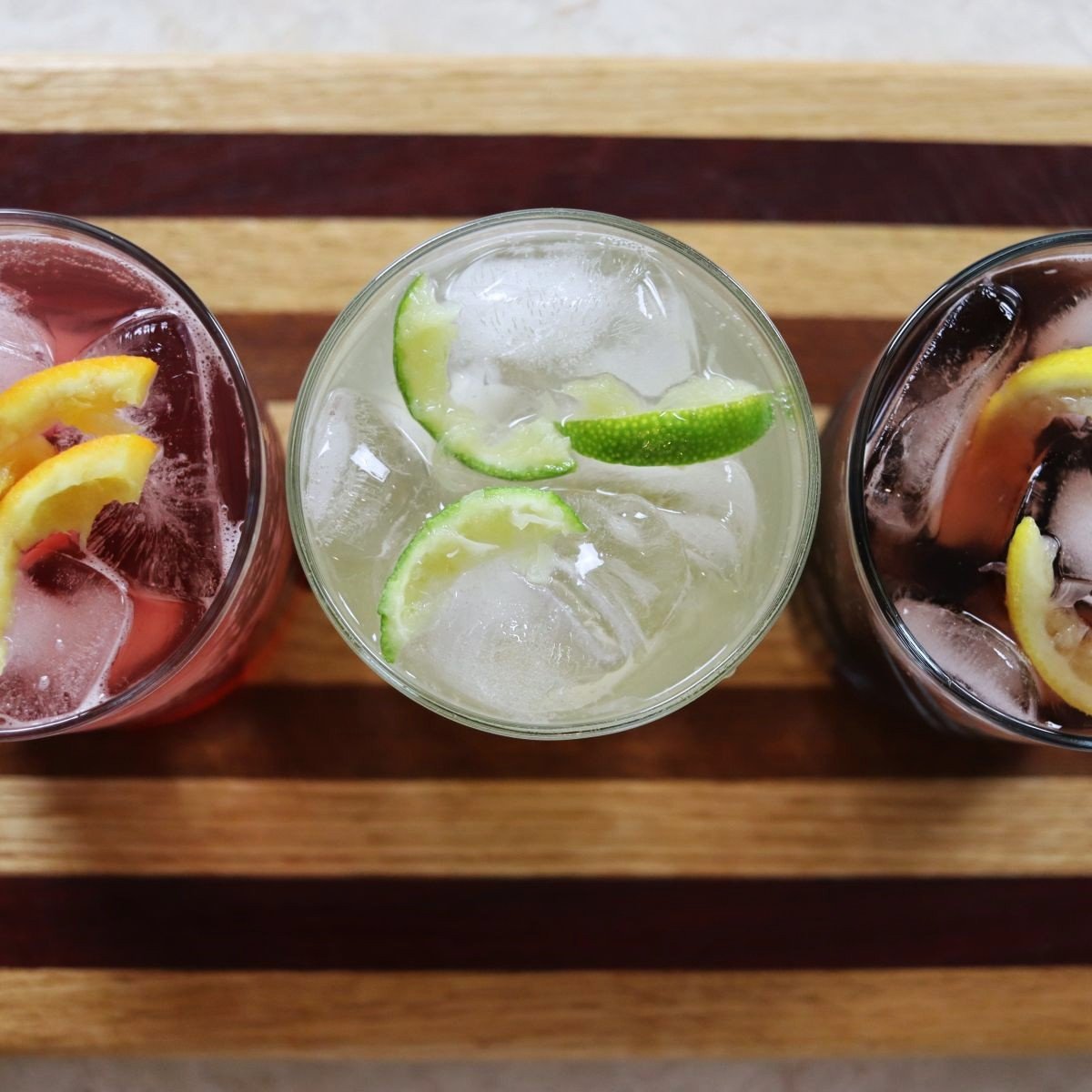 overview of three mocktails with citrus garnishes sitting on a cutting board.